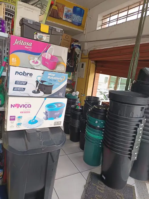 Caixas de mops giratórios empilhadas ao lado de pilhas de baldes e lixeiras